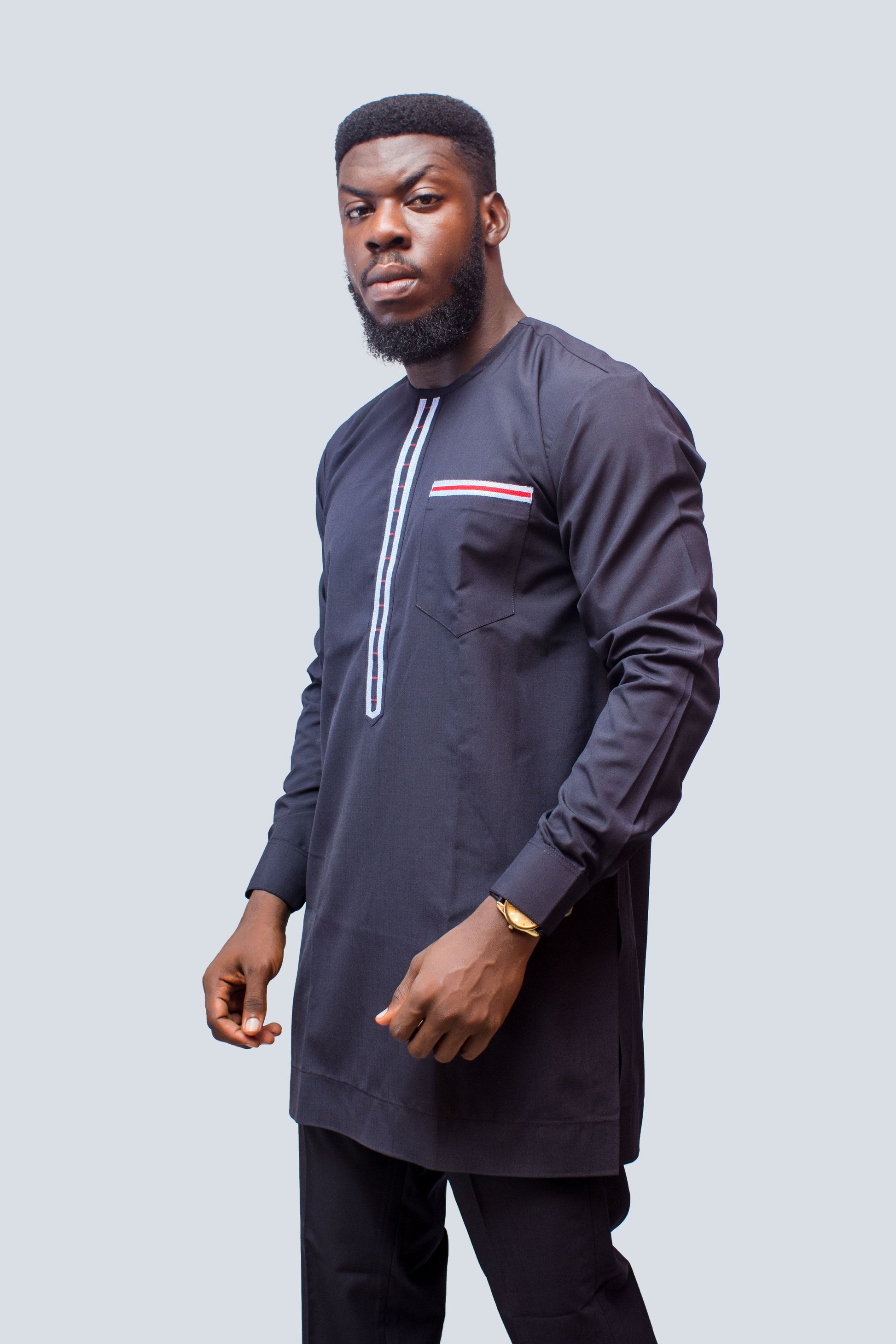 African Men's Suit featuring a longline navy blue tunic with a round neckline, a central vertical white placket detail accented by light blue and red threading, a matching decorated chest pocket welt, and tailored coordinating trousers