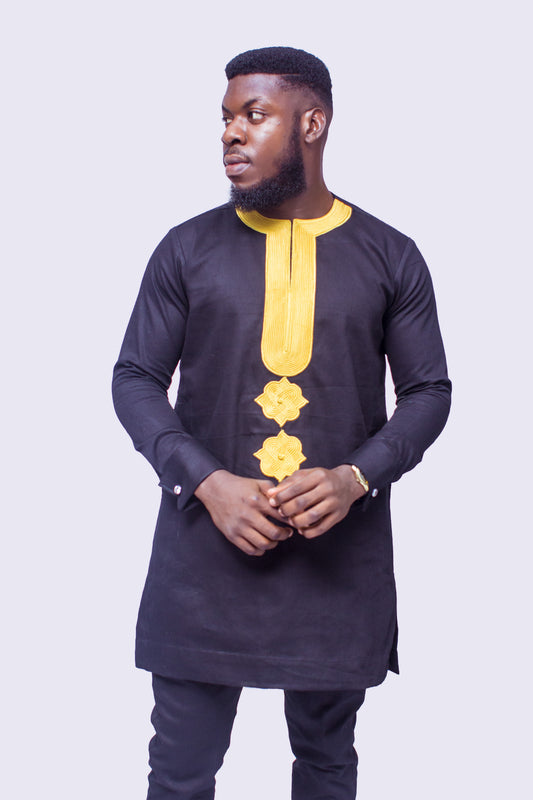 African Suit featuring a longline black tunic with a gold embroidered round neckline, a central embroidered vertical panel, two matching gold geometric chest medallions, and coordinating tailored trousers