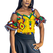 Ankara Top featuring a cold-shoulder crop silhouette with elasticated flare sleeves in a colorful geometric print with yellow, blue, red, and green diamond and triangle motifs