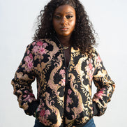 Gilded Rose Floral Bomber Jacket  featuring a black velvet-texture fabric with intricate pink rose and gold scrollwork patterns. Front View