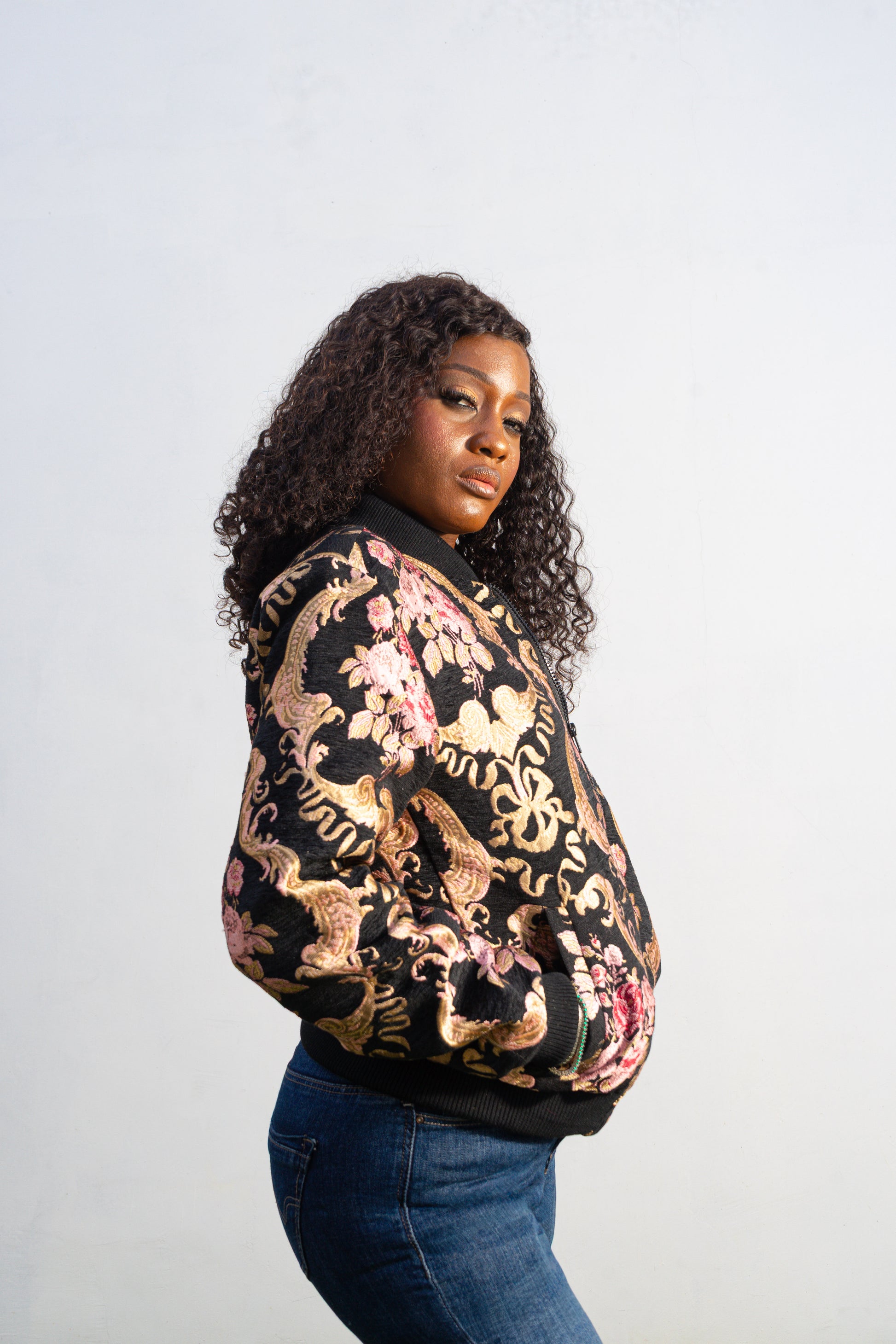 Gilded Rose Floral Bomber Jacket featuring a black velvet-texture fabric with intricate pink rose and gold scrollwork patterns. Side View