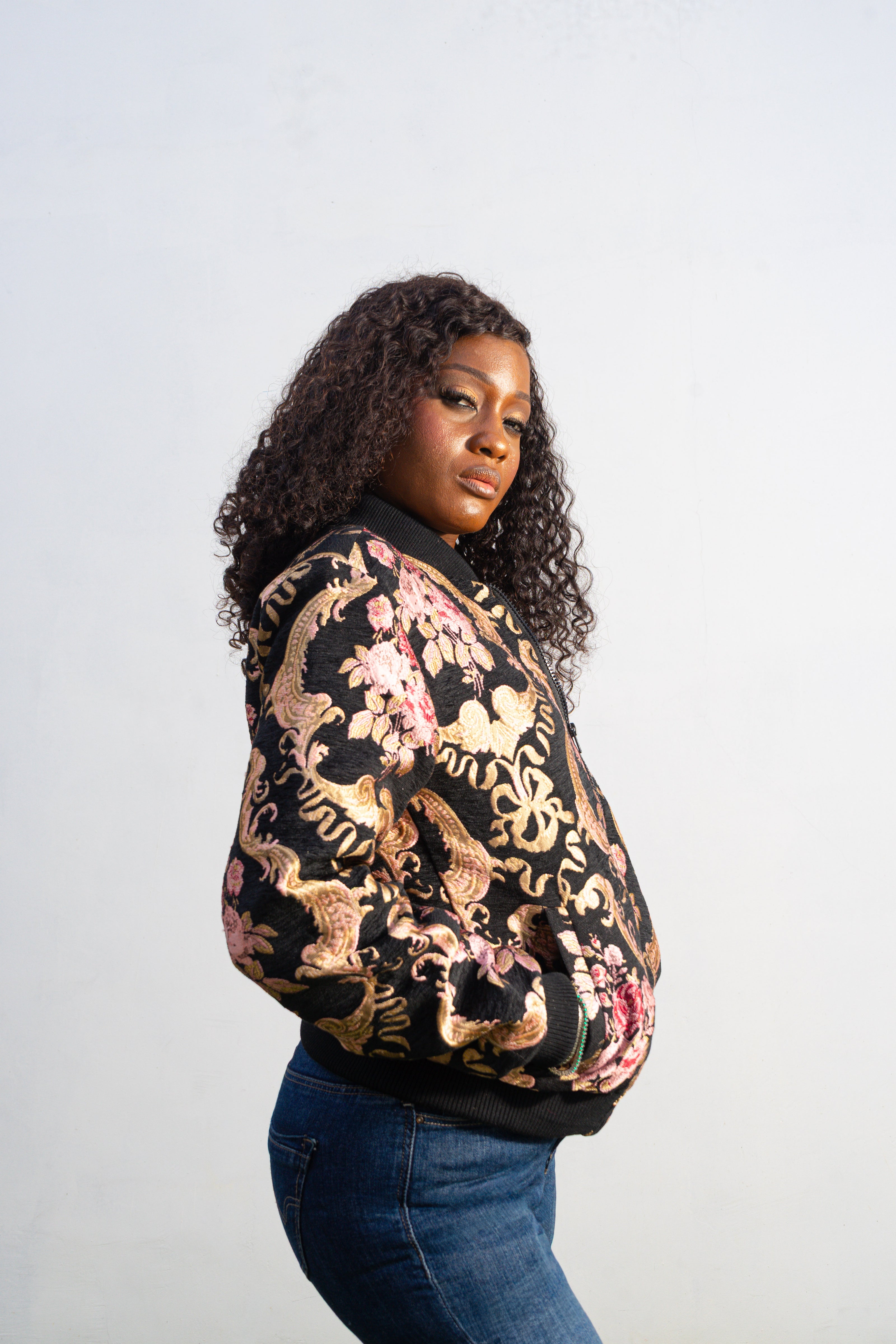 Gilded Rose Floral Bomber Jacket featuring a black velvet-texture fabric with intricate pink rose and gold scrollwork patterns. Side View