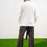 Boot-cut pants featuring a brown and black checkered pattern, a high-waisted design with a large matching fabric waist tie, and a flared leg opening.
