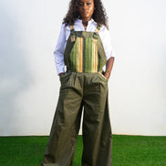 Verdant Patchwork Cotton Jumpsuit featuring wide-leg olive trousers and a bib panel with green, black, and orange vertical stripes. 
