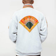 Dashiki Bomber Jacket featuring a light grey body with a striking orange, yellow, and green traditional African print on the high collar, chest panel, front pouch pocket, and sleeve borders