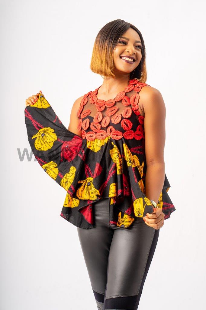 Handkerchief Top featuring a sheer mesh upper bodice adorned with textured red lace floral details, transitioning into a flared, asymmetrical black Ankara printed peplum with bold yellow and red patterns
