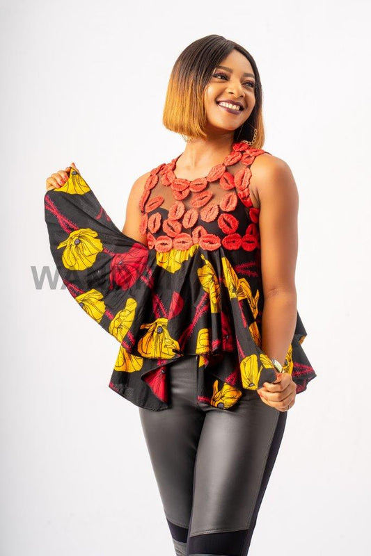 Handkerchief Top featuring a sheer mesh upper bodice adorned with textured red lace floral details, transitioning into a flared, asymmetrical black Ankara printed peplum with bold yellow and red patterns