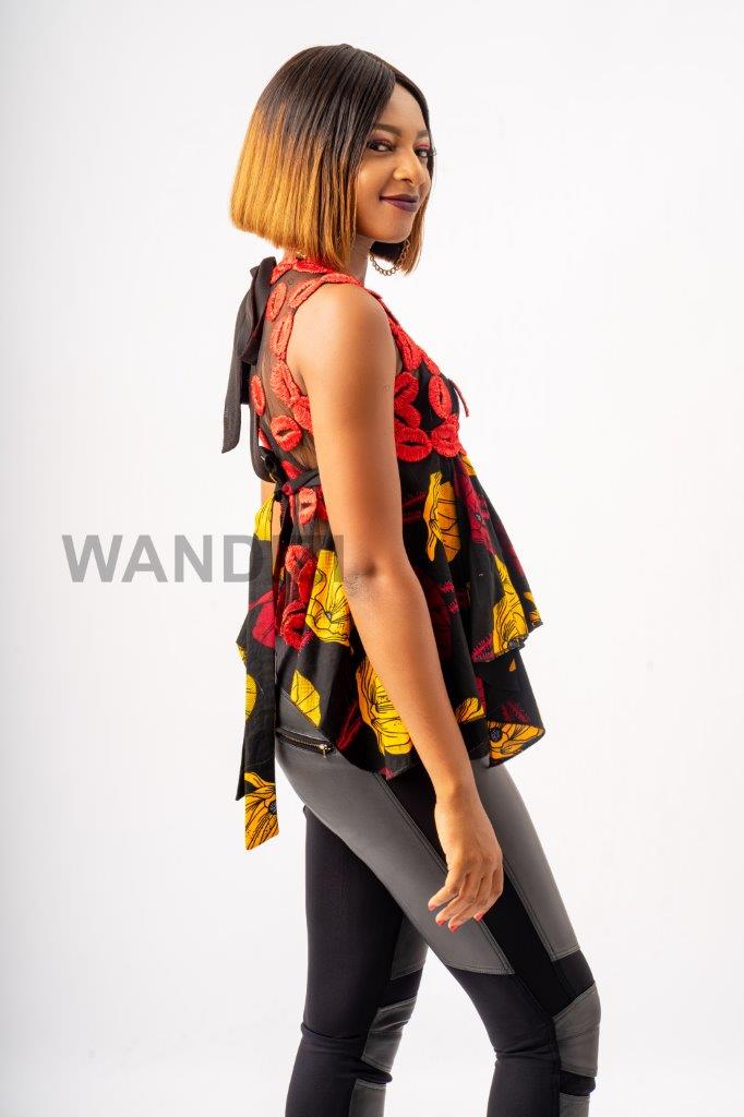 Handkerchief Top featuring a sheer mesh upper bodice adorned with textured red lace floral details, transitioning into a flared, asymmetrical black Ankara printed peplum with bold yellow and red patterns