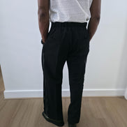 High-Waisted Trousers featuring black micro-textured wide-leg pants with a high structured waistband and side-zip closure. Back View.