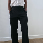High-Waisted Trousers featuring black micro-textured wide-leg pants with a high structured waistband and side-zip closure.