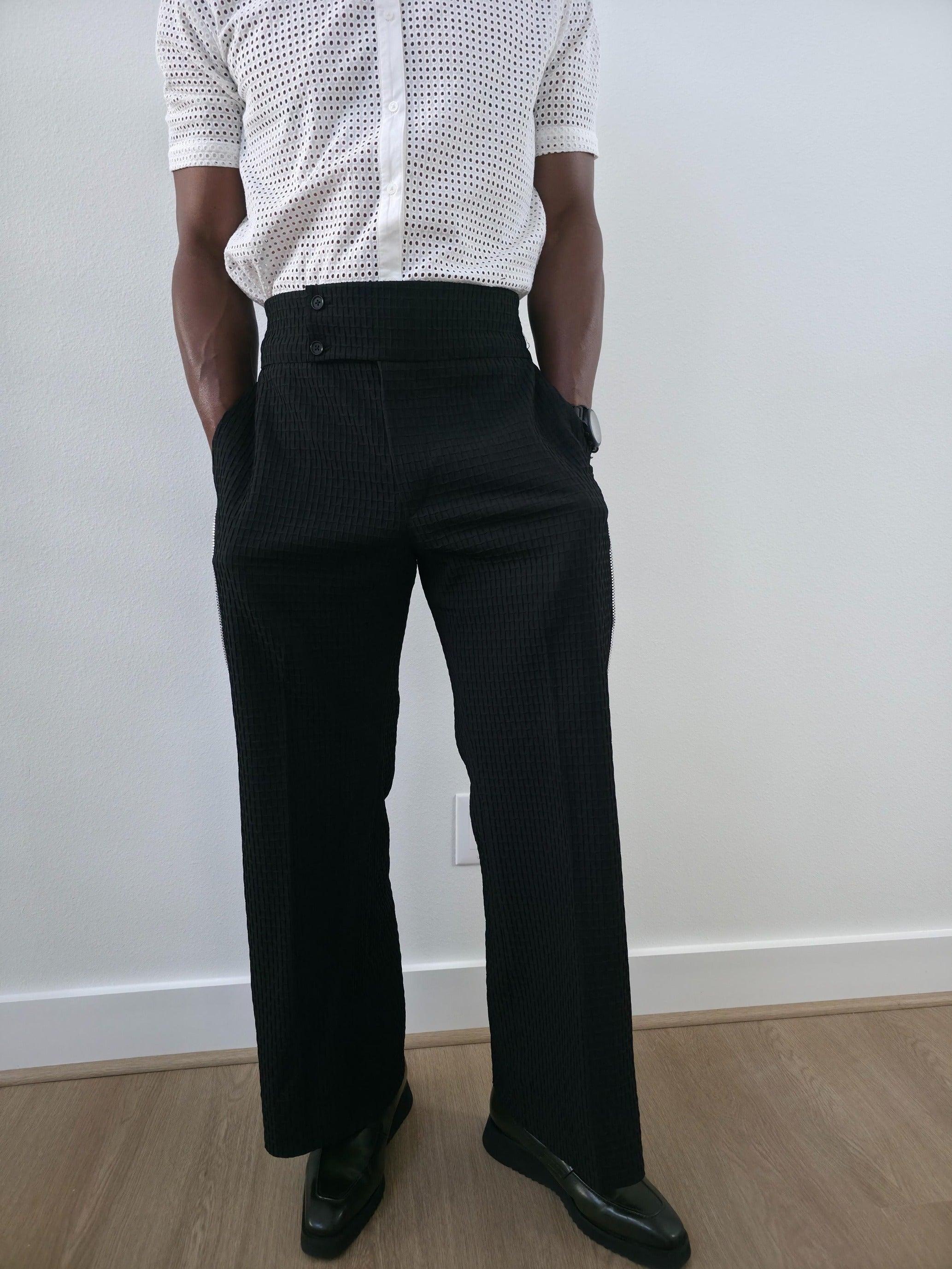 High-Waisted Trousers featuring black micro-textured wide-leg pants with a high structured waistband and side-zip closure.