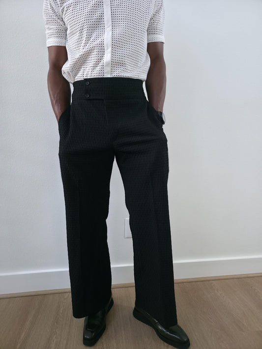 High-Waisted Trousers featuring black micro-textured wide-leg pants with a high structured waistband and side-zip closure.