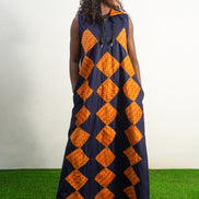 Orange and black Diamond Patterned Jumpsuit featuring a sleeveless black frame with large orange diamond-shaped patchwork across the front and an attached hood. Front View