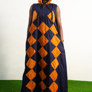 Orange and black Diamond Patterned Jumpsuit featuring a sleeveless black frame with large orange diamond-shaped patchwork across the front and an attached hood. Hoody On Posing