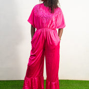 Smocked Pink Jumpsuit  featuring a vibrant fuchsia fabric with a beaded V-shape design on the bodice, short flutter sleeves, and ruffled ankle hems.