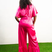 Smocked Pink Jumpsuit featuring a vibrant fuchsia fabric with a beaded V-shape design on the bodice, short flutter sleeves, and ruffled ankle hems. Back View