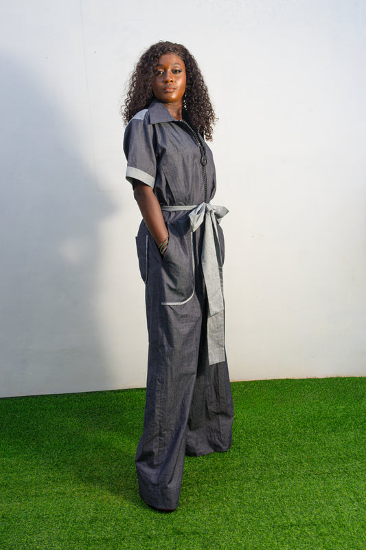 Trendy Denim Jean Jumpsuit (image_8f4b3e.jpg) featuring a deep indigo denim fabric, light-wash contrast trim on the short sleeves and pockets, and a matching light-wash denim waist tie. Side View