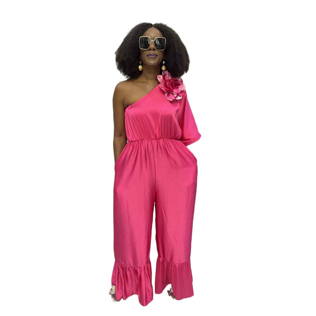 Magenta Jumpsuit featuring a one-shoulder neckline with a large pink floral detail, an elasticated waist, and wide-leg trousers with ruffled hems.