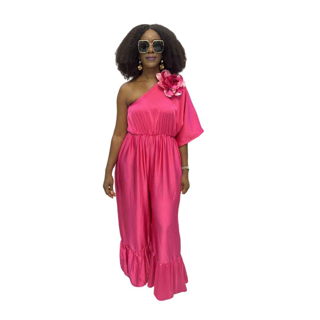 Magenta Jumpsuit featuring a one-shoulder neckline with a large pink floral detail, an elasticated waist, and wide-leg trousers with ruffled hems.