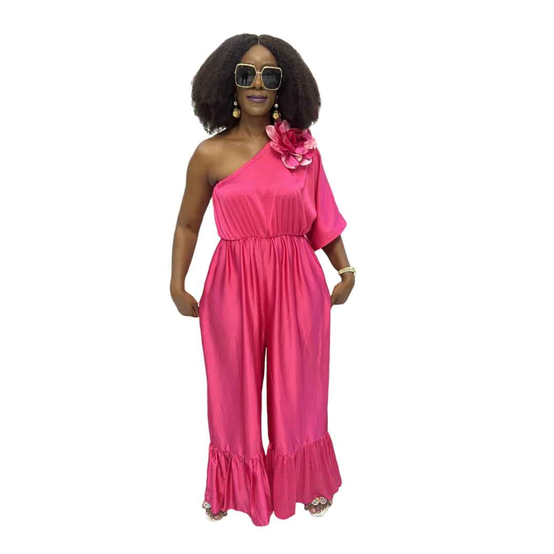 Magenta Jumpsuit featuring a one-shoulder neckline with a large pink floral detail, an elasticated waist, and wide-leg trousers with ruffled hems.
