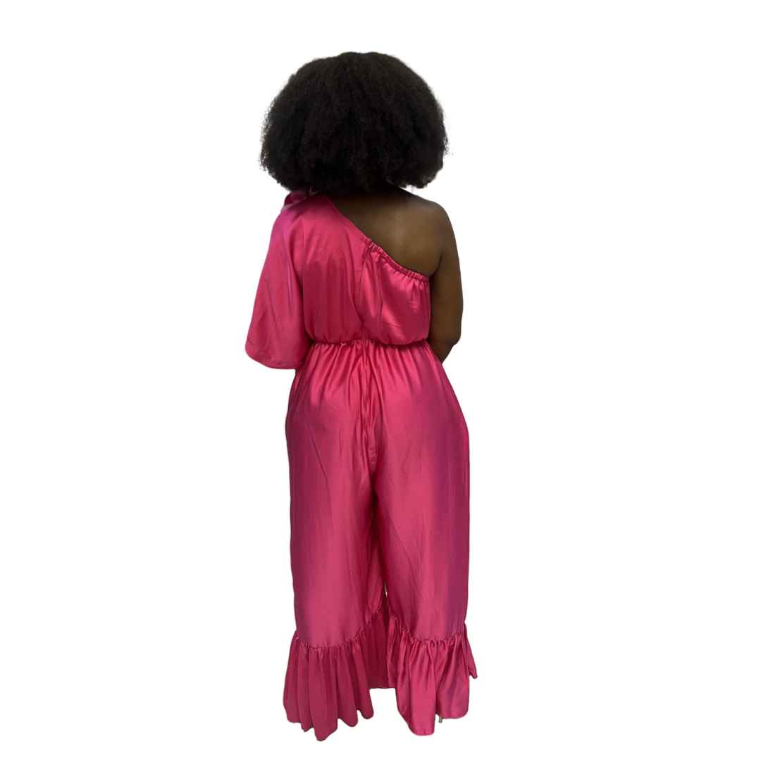 Magenta Jumpsuit featuring a one-shoulder neckline with a large pink floral detail, an elasticated waist, and wide-leg trousers with ruffled hems.