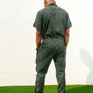 Short-sleeved utility jumpsuit featuring an olive green animal camouflage pattern, a front zipper, and a black bomber-style collar.