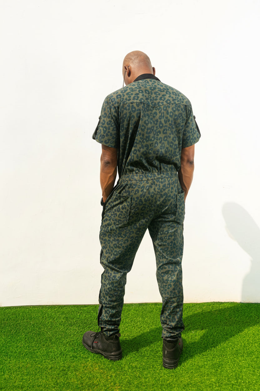 Short-sleeved utility jumpsuit featuring an olive green animal camouflage pattern, a front zipper, and a black bomber-style collar.