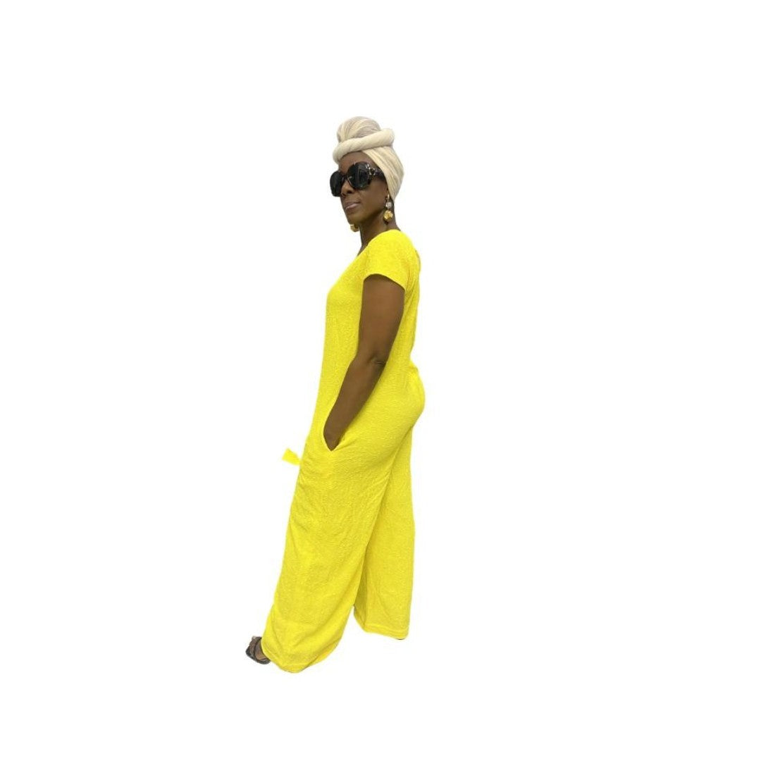 Jumpsuit featuring a sleeveless V-neckline, a prominent matching yellow neck tie, and long wide-leg trousers