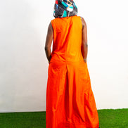 Jumpsuit featuring a vibrant solid orange hue, a deep V-neckline with a metal zipper and black pull cords, and a modern hoodie lined with an intricate, multi-colored Afrocentric pattern.Back View