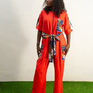 Chic Orange Jumpsuit with a colorful tassel  featuring a bright orange fabric, short sleeves, a patterned chest pocket, and a matching colorful patterned waist belt.  Female's Clothing
