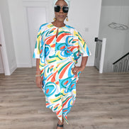Abstract Aurora Boubou Kaftan featuring a colorful turquoise, orange, and yellow swirl pattern on white silk-satin with a mint headwrap. Front Pose