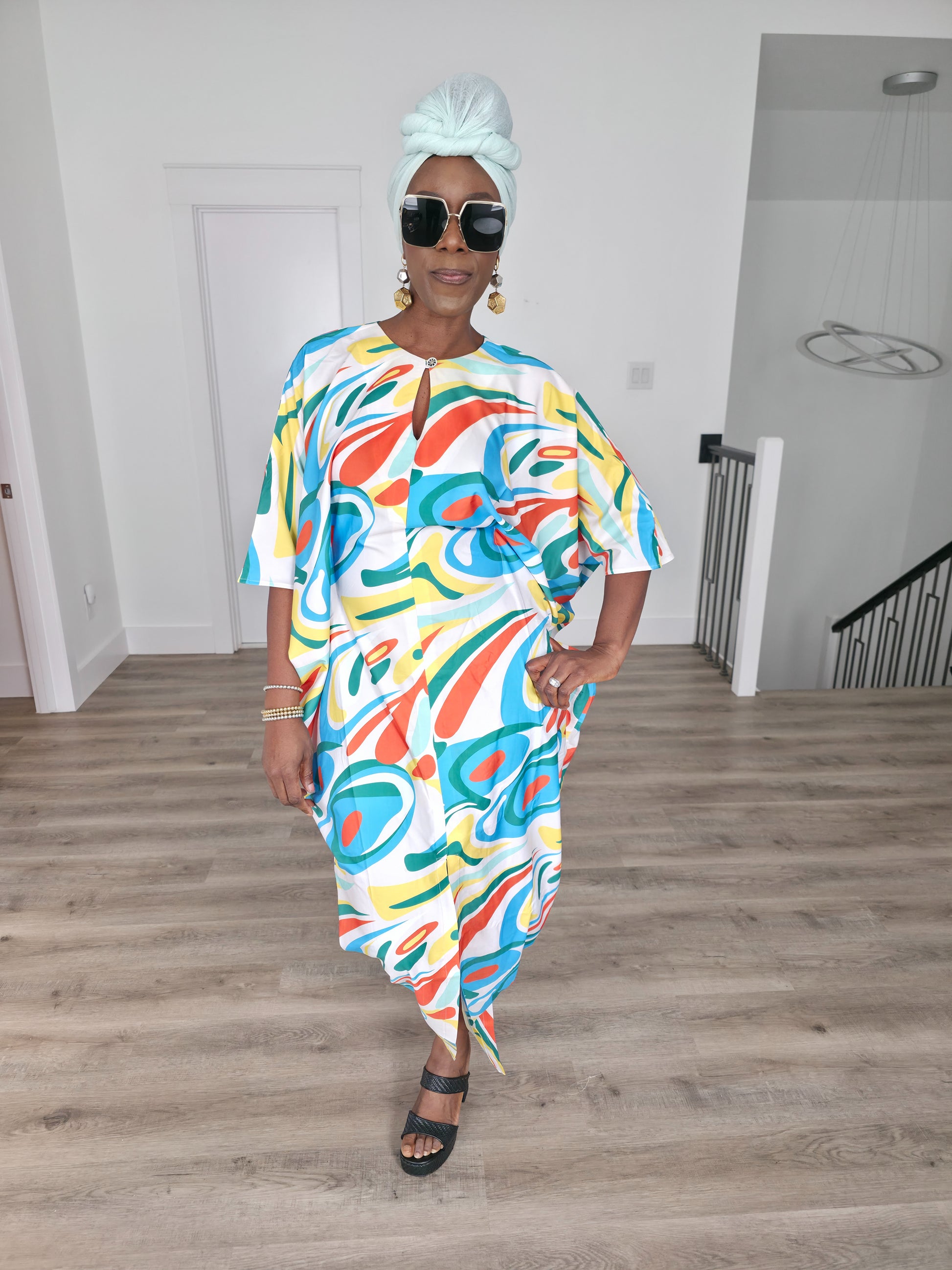 Abstract Aurora Boubou Kaftan featuring a colorful turquoise, orange, and yellow swirl pattern on white silk-satin with a mint headwrap. Front Pose
