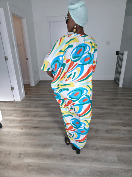 Abstract Aurora Boubou Kaftan featuring a colorful turquoise, orange, and yellow swirl pattern on white silk-satin with a mint headwrap. Back View