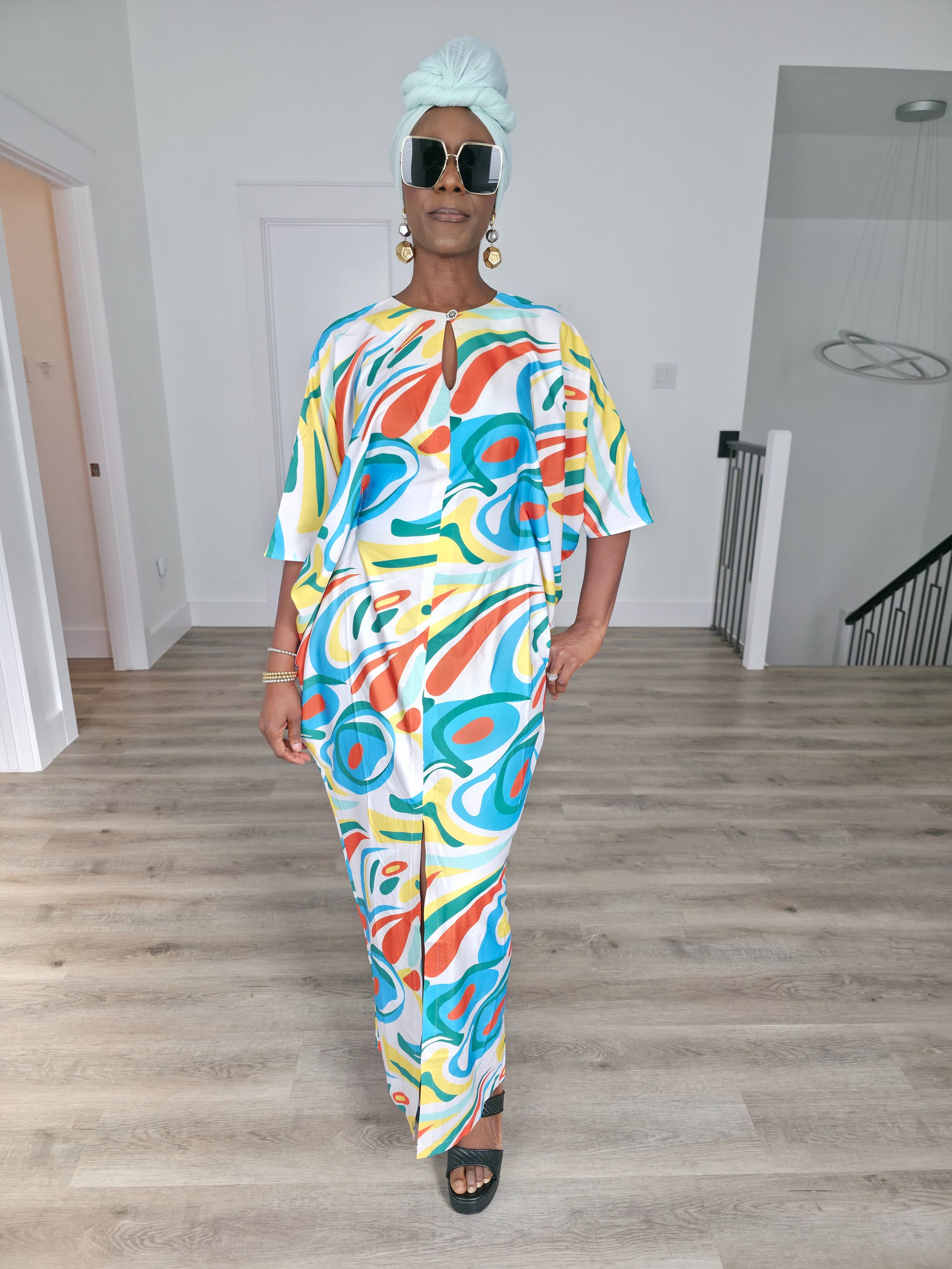 Abstract Aurora Boubou Kaftan featuring a colorful turquoise, orange, and yellow swirl pattern on white silk-satin with a mint headwrap. Front View