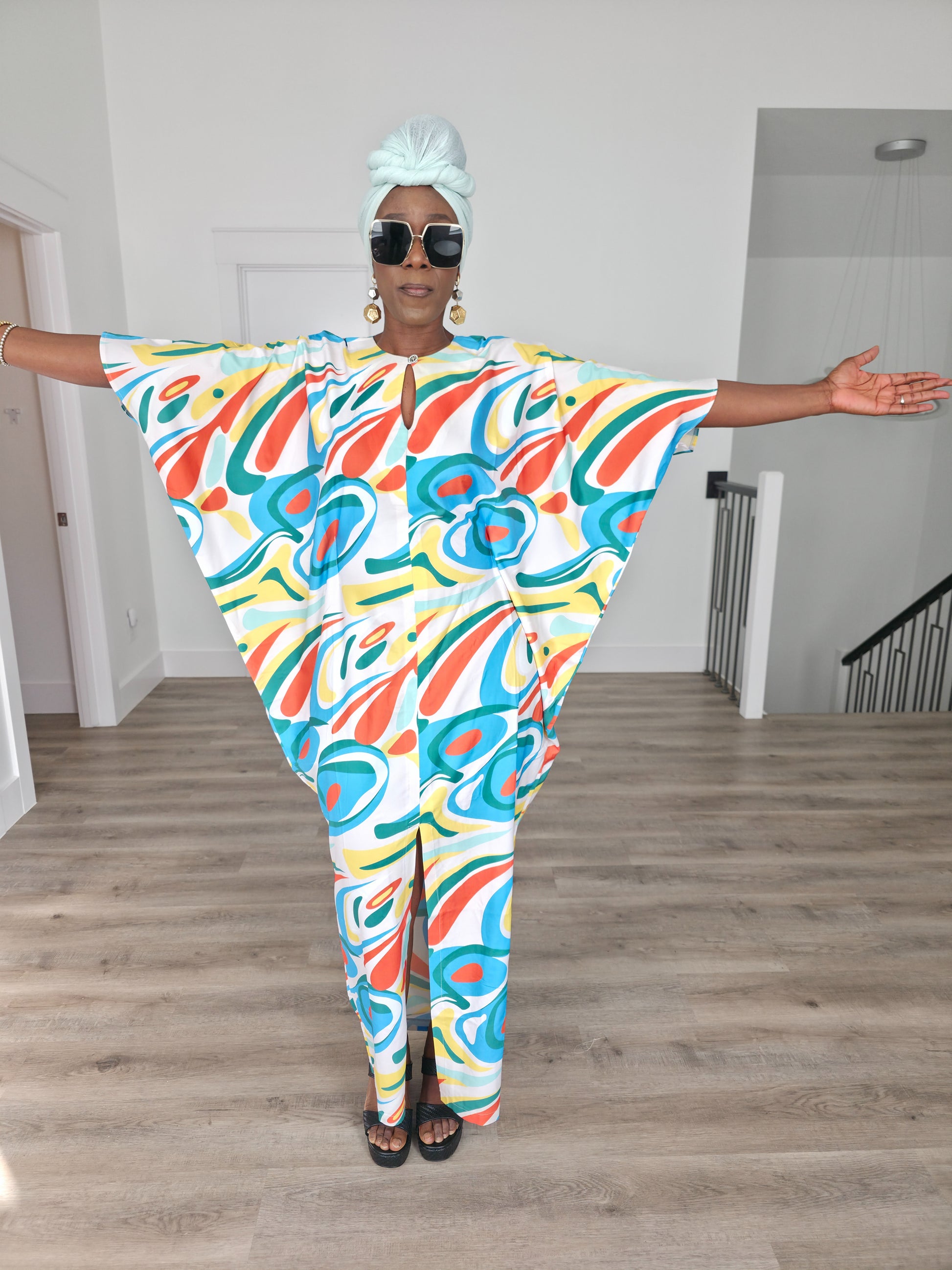 Abstract Aurora Boubou Kaftan featuring a colorful turquoise, orange, and yellow swirl pattern on white silk-satin with a mint headwrap. Spread out Full view