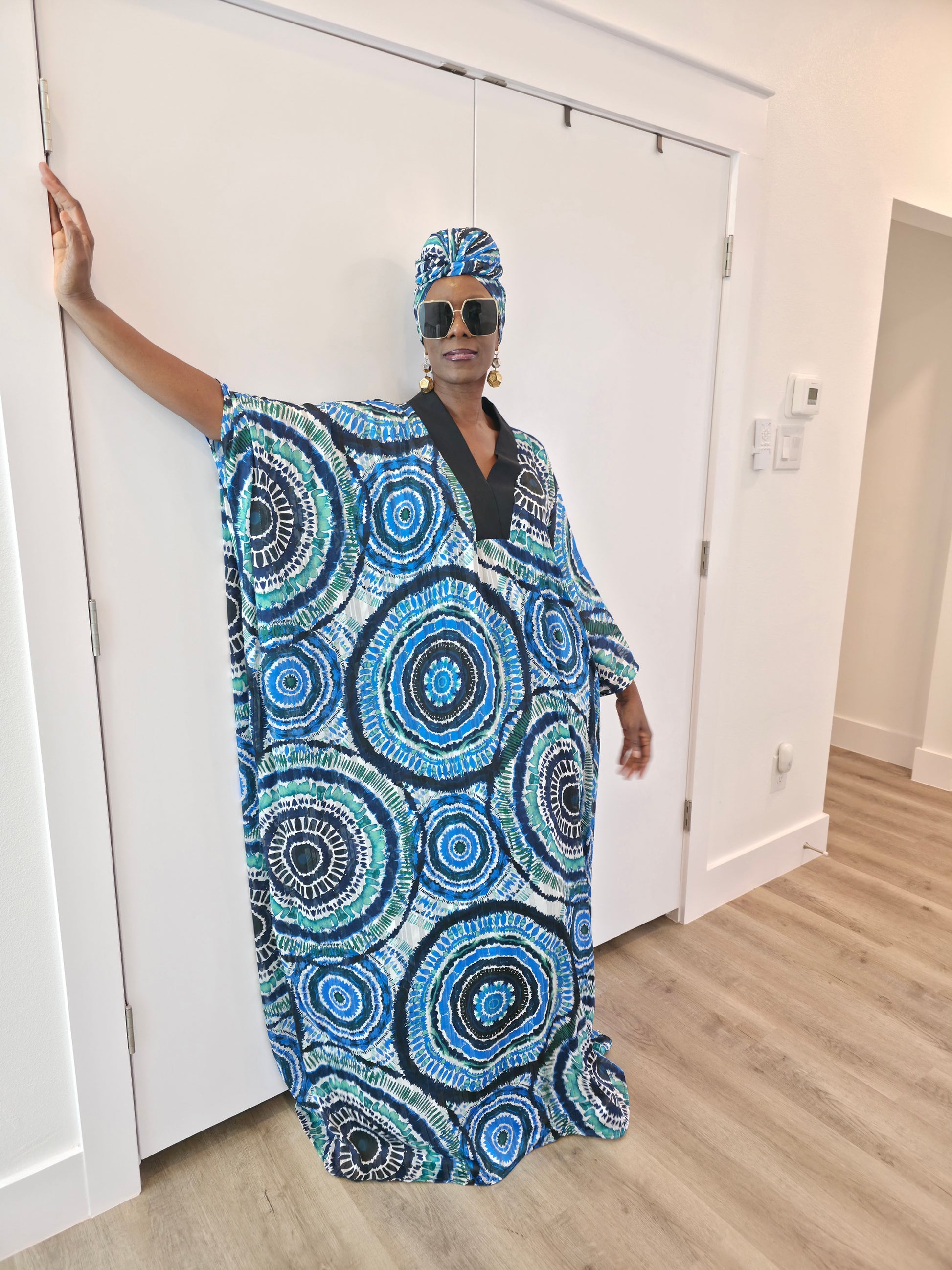 Patterned Boubou Kaftan featuring a blue and turquoise concentric circular print, a solid black V-neckline, and a voluminous silhouette.