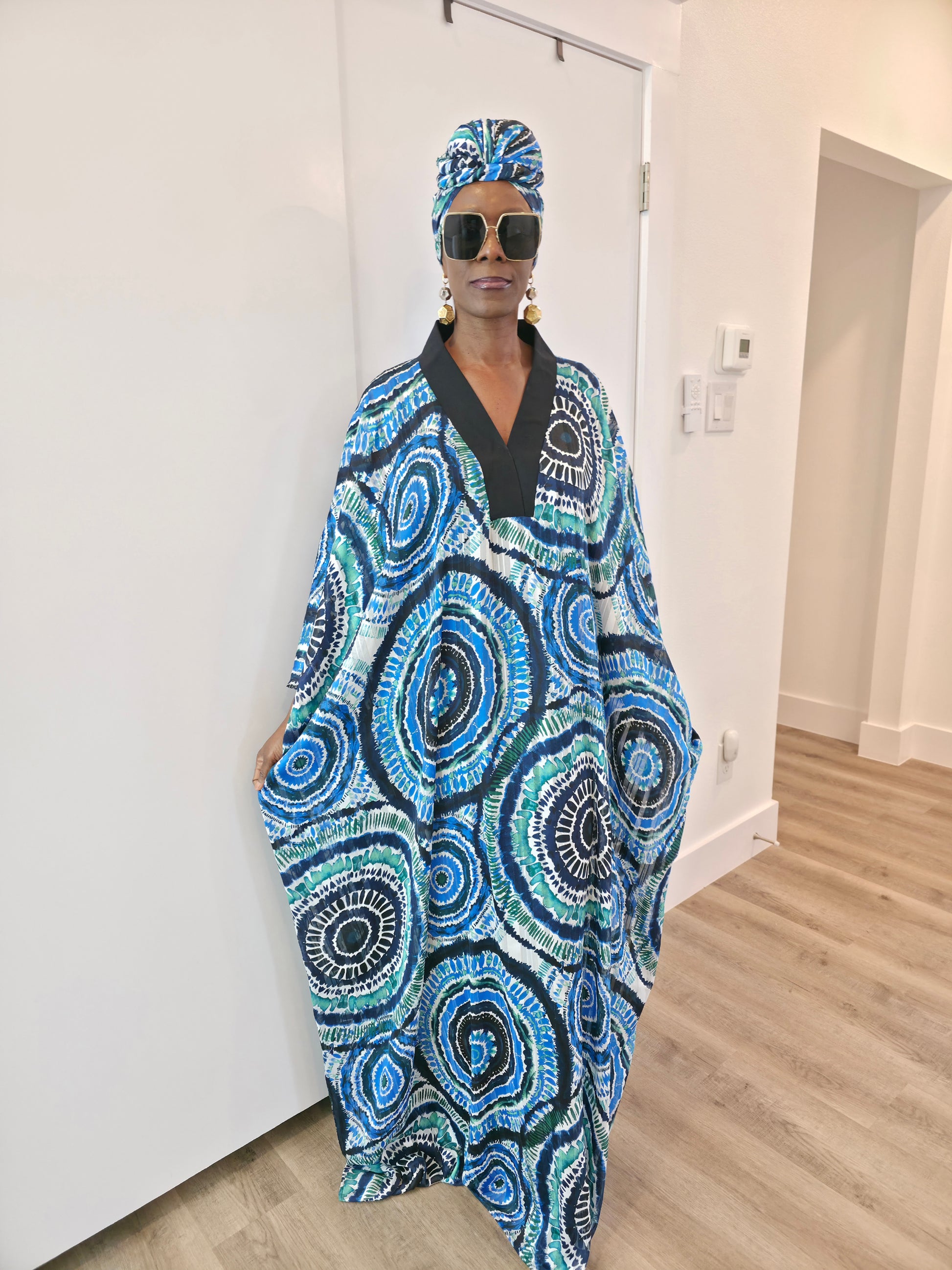 Patterned Boubou Kaftan featuring a blue and turquoise concentric circular print, a solid black V-neckline, and a voluminous silhouette.