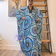 Patterned Boubou Kaftan featuring a blue and turquoise concentric circular print, a solid black V-neckline, and a voluminous silhouette.