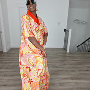 Citrus Sorbet Boubou Kaftan featuring a vibrant pink, orange, and yellow organic swirl pattern with a structured orange V-neck collar. Front View