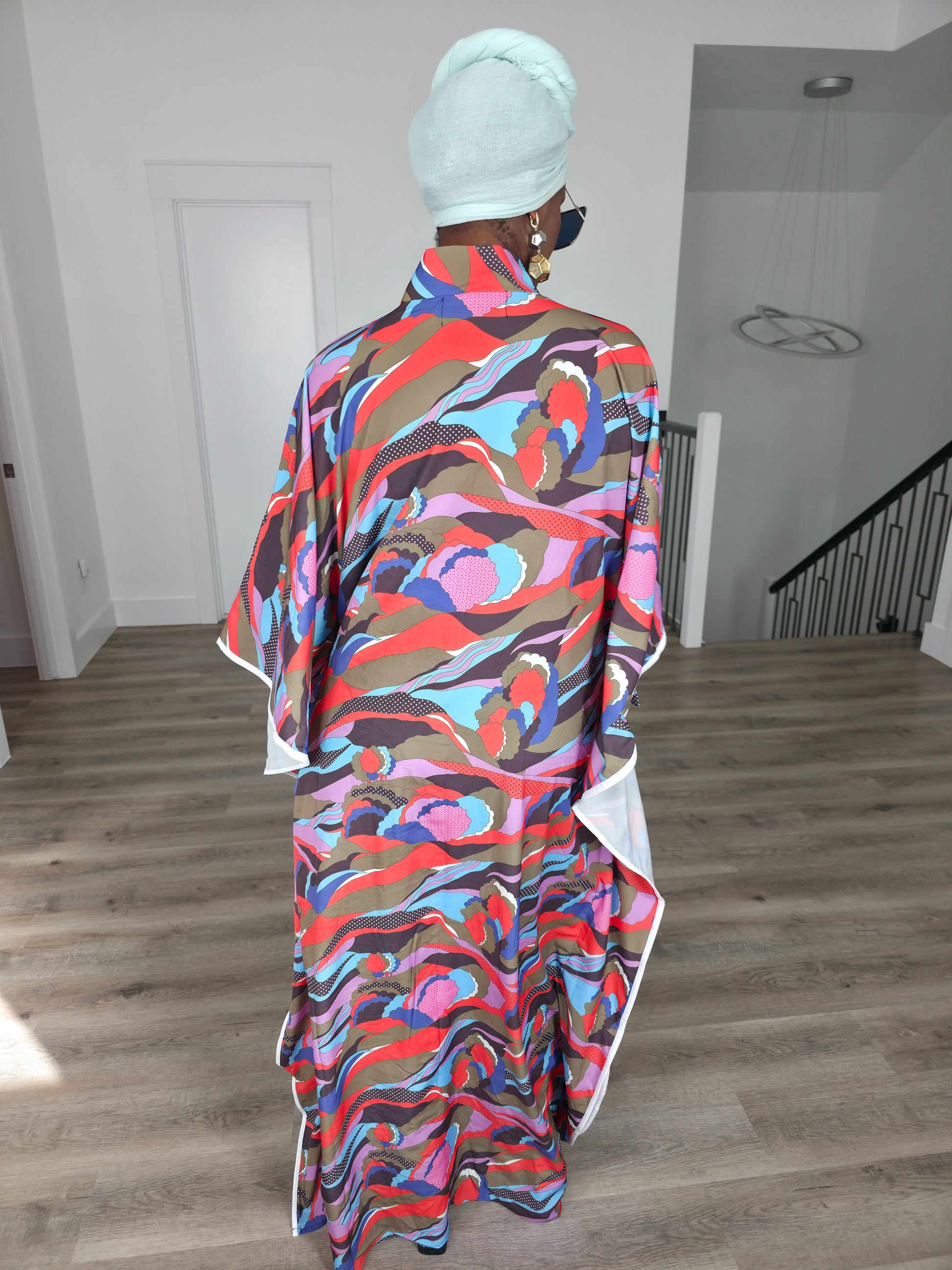 Desert Wildflower Boubou Kaftan featuring a colorful abstract organic print in earth tones, blue, and pink with a mint green headwrap. Back View