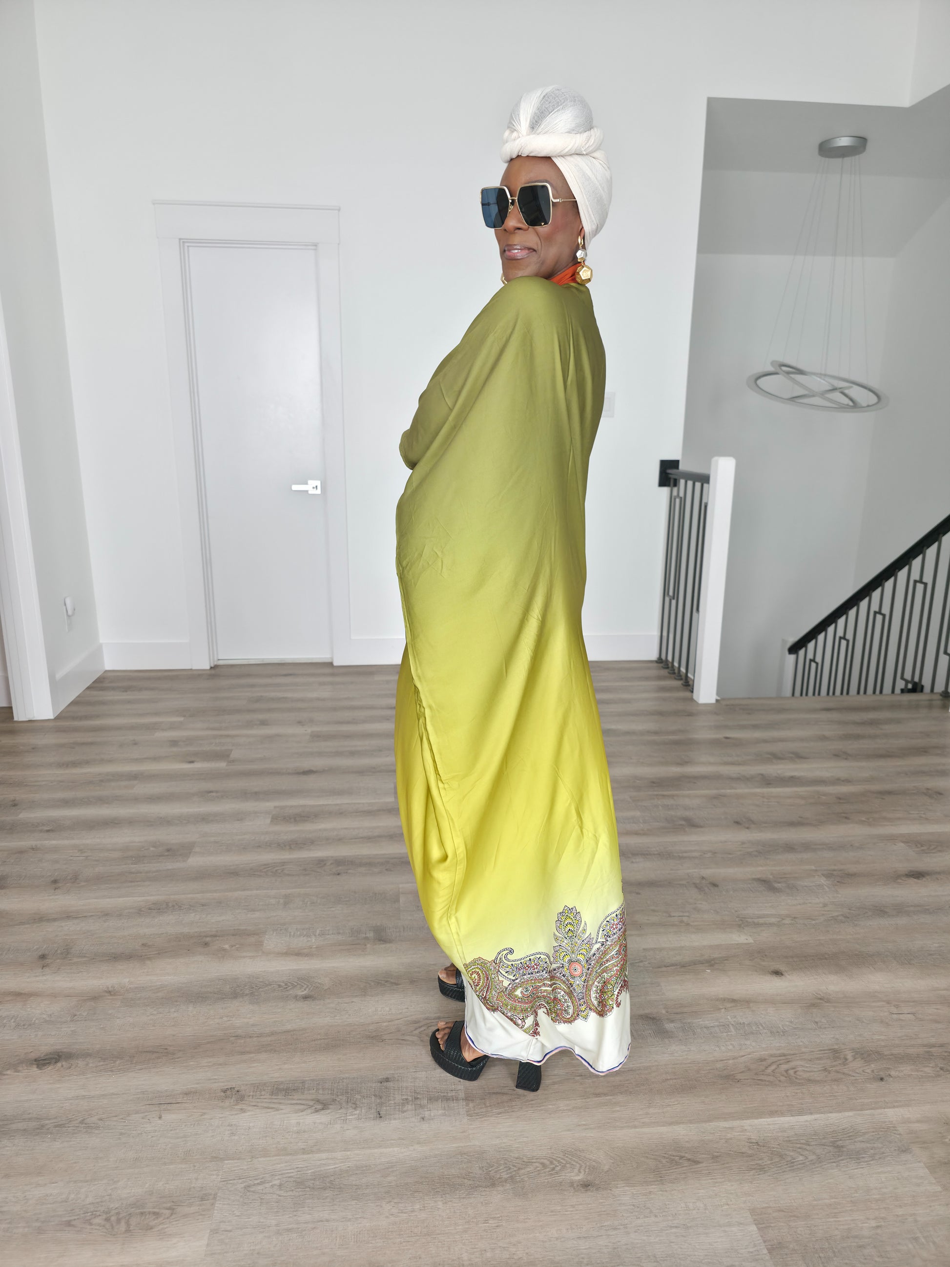 Gilded Olive Boubou Kaftan featuring an olive green and yellow gradient design with an orange V-neck collar and intricate paisley patterns along the hem. Side View