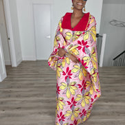 Hibiscus Sorbet Boubou Kaftan featuring a light pink fabric with large yellow and red floral prints and a structured deep red V-neck collar.