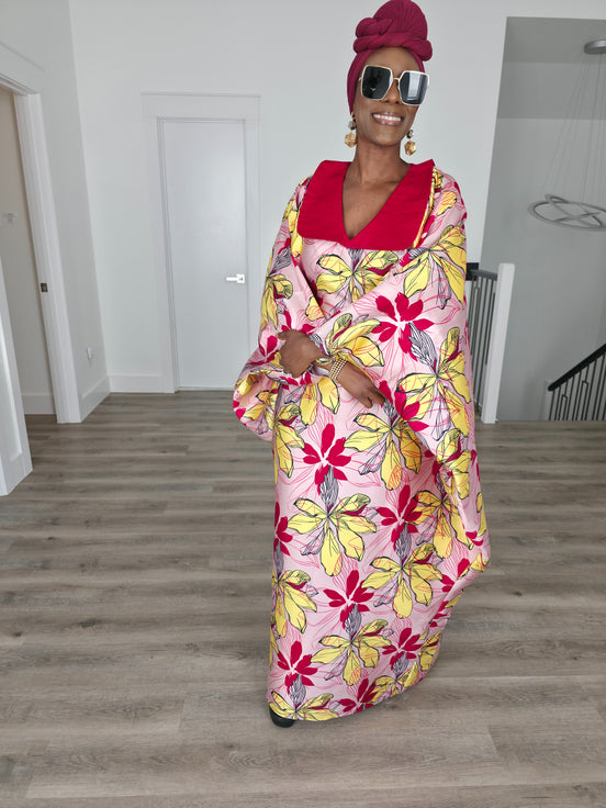 Hibiscus Sorbet Boubou Kaftan featuring a light pink fabric with large yellow and red floral prints and a structured deep red V-neck collar.