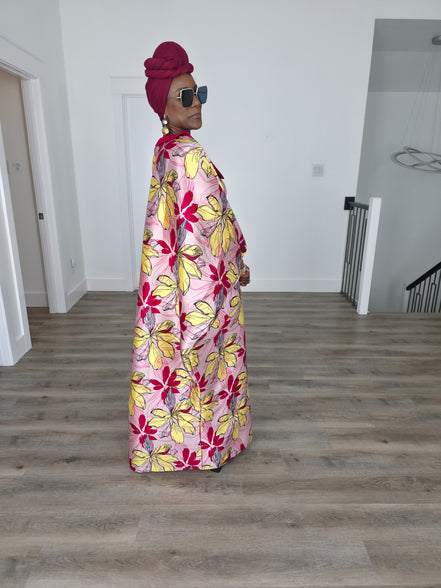 Hibiscus Sorbet Boubou Kaftan featuring a light pink fabric with large yellow and red floral prints and a structured deep red V-neck collar. Side View 