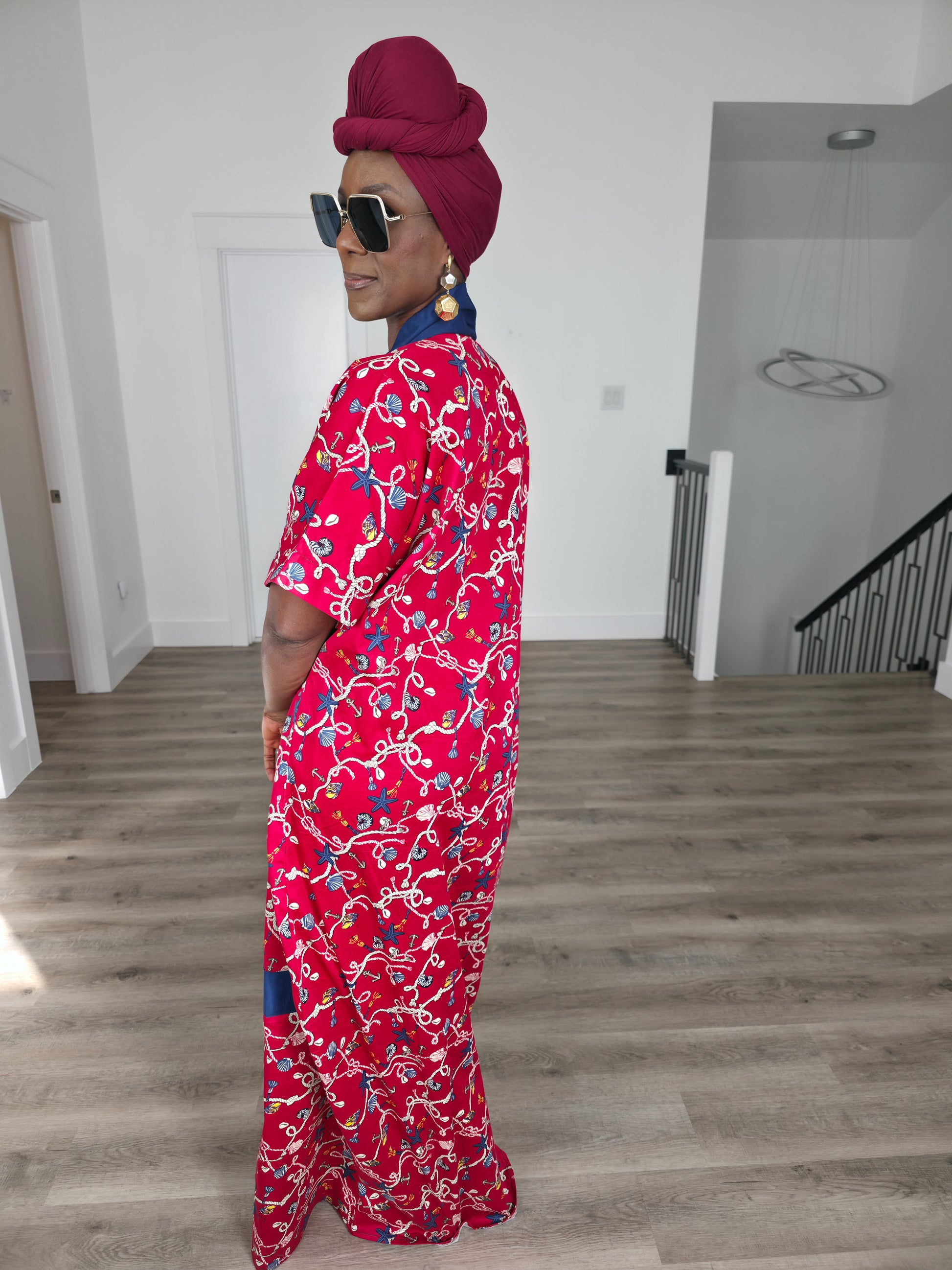 Midnight Poppy Boubou Kaftan in deep red with a white and blue floral print, featuring a navy blue collar and matching burgundy headwrap. Side back view