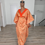 Molten Ember Boubou Kaftan in copper and orange abstract print with a solid orange V-neckline and a white headwrap. Front