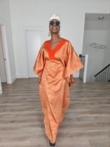 Molten Ember Boubou Kaftan in copper and orange abstract print with a solid orange V-neckline and a white headwrap. Front
