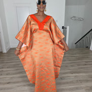 Molten Ember Boubou Kaftan in copper and orange abstract print with a solid orange V-neckline and a white headwrap. Women's Wear