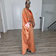Molten Ember Boubou Kaftan in copper and orange abstract print with a solid orange V-neckline and a white headwrap. Side View