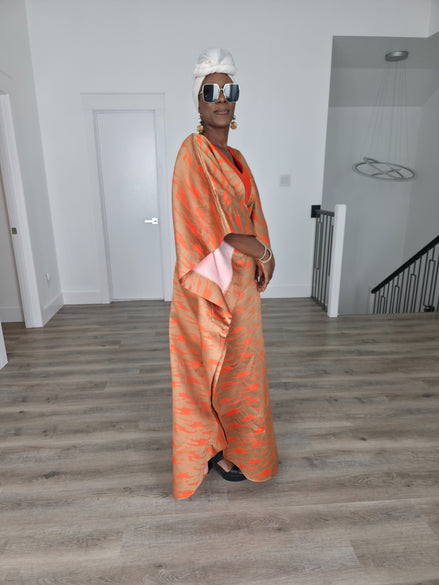 Molten Ember Boubou Kaftan in copper and orange abstract print with a solid orange V-neckline and a white headwrap. Side View